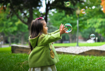 photo of a child playing with bubbles in a park