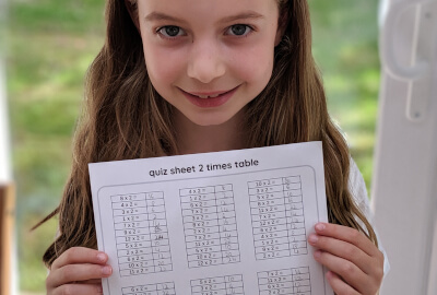 photo showing girl holding 2 times table sheet