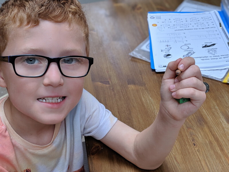 photo showing boy holding eraser in last 2 fingers of left hand whilst holding a pencil